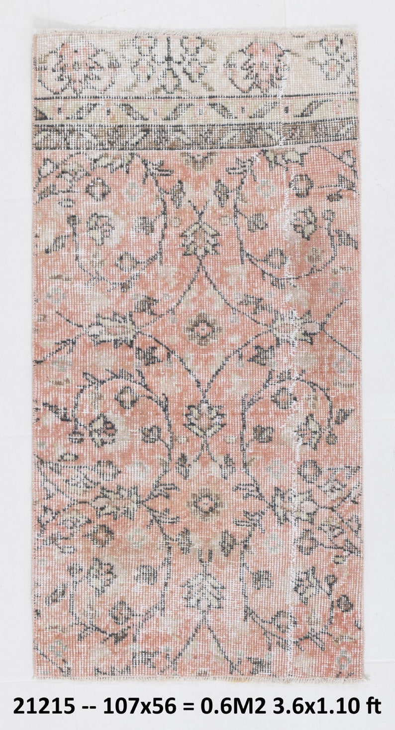 May include: A vintage pink and cream rug with a floral pattern. The rug is approximately 3.6 feet by 1.1 feet.