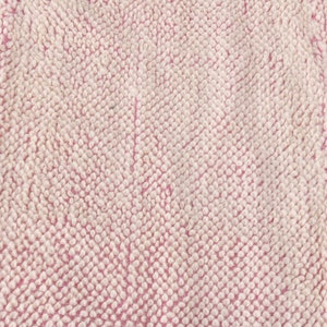 May include: Close-up of a pink and white textured fabric with a soft, fuzzy surface.