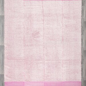 May include: A pink and white fluffy rug with a pink border. The rug has a textured surface and is made of a soft material.