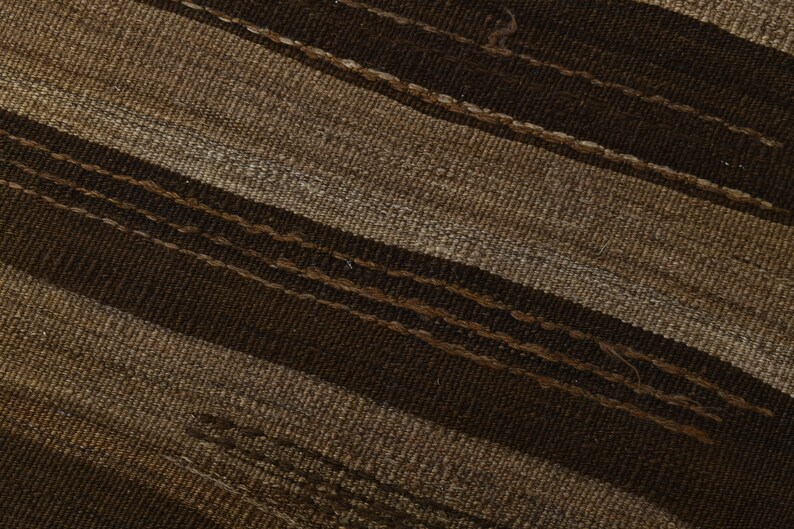 May include: Close-up of a woven fabric with brown and beige stripes. The fabric has a textured surface and a diagonal pattern.