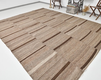 May include: A woven rug with a geometric pattern of brown stripes on a beige background.