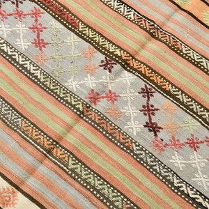 May include: A striped rug with a geometric pattern in shades of brown, pink, white, and green.