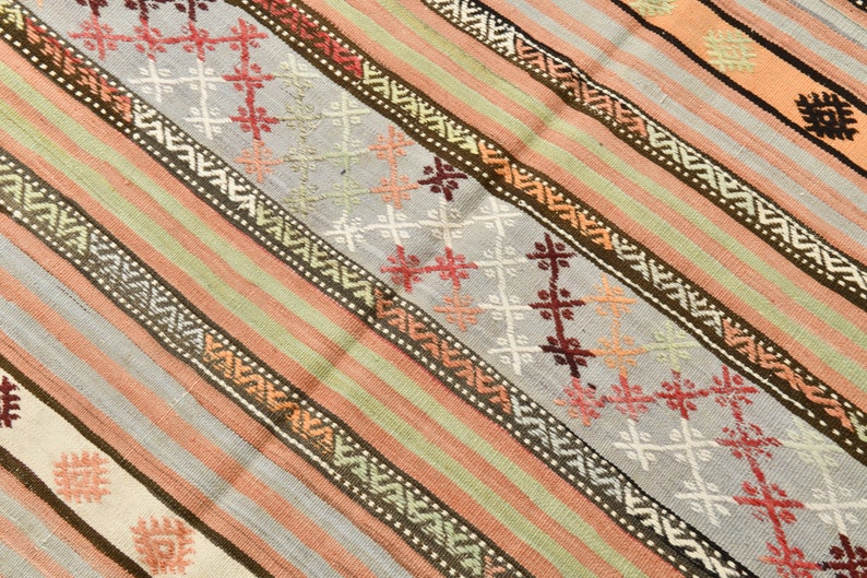 May include: A striped rug with a geometric pattern in shades of brown, pink, white, and green.