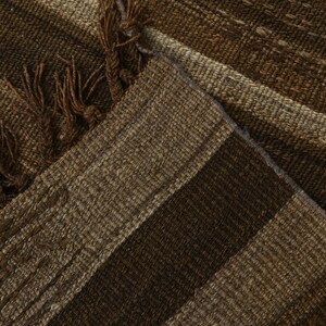 May include: Close-up of a brown and beige striped woven rug with fringe on the edges.