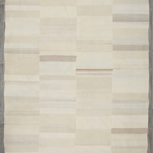 May include: A white and cream striped rug with a subtle woven pattern. The rug is made of natural fibers and has a rustic, hand-woven look. It measures 11.1 x 7.1 feet.