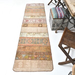 May include: A long, rectangular rug with a patchwork design. The rug is made of different colored fabrics with geometric patterns. The rug is beige, brown, and orange with a hint of pink.