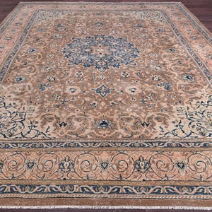May include: A large, rectangular area rug with an intricate floral pattern. The rug features a central medallion in shades of blue, surrounded by a beige and peach field. The border is a darker blue with floral motifs, creating a classic, elegant look.