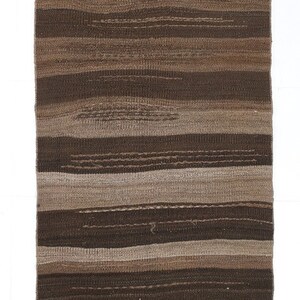 May include: A brown and beige striped woven rug with fringe on the ends.