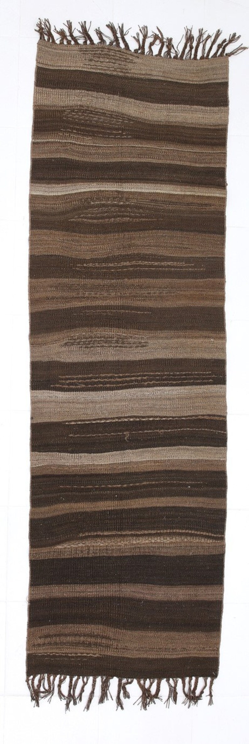 May include: A brown and beige striped woven rug with fringe on the ends.