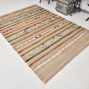 May include: A beige, brown, and pink striped rug with a geometric pattern. The rug has a distressed, vintage look.