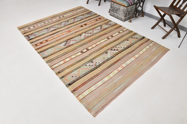 May include: A beige, brown, and pink striped rug with a geometric pattern. The rug has a distressed, vintage look.