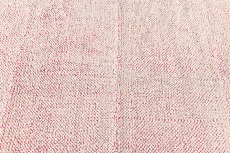 May include: Close-up of a pink and white textured fabric. The fabric has a soft, fuzzy texture.