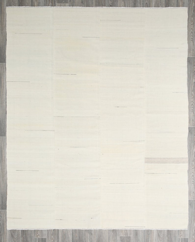 May include: A white woven rug with a subtle texture. The rug has a simple, minimalist design and is perfect for adding a touch of elegance to any room.