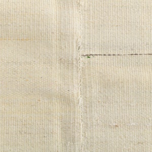 May include: Close-up of a white woven fabric with a seam running down the center.