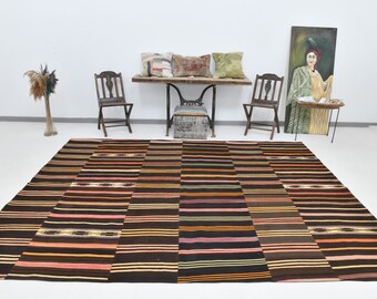 May include: A brown and beige striped rug with a patchwork design. The rug is made of woven fabric and has a rustic look.