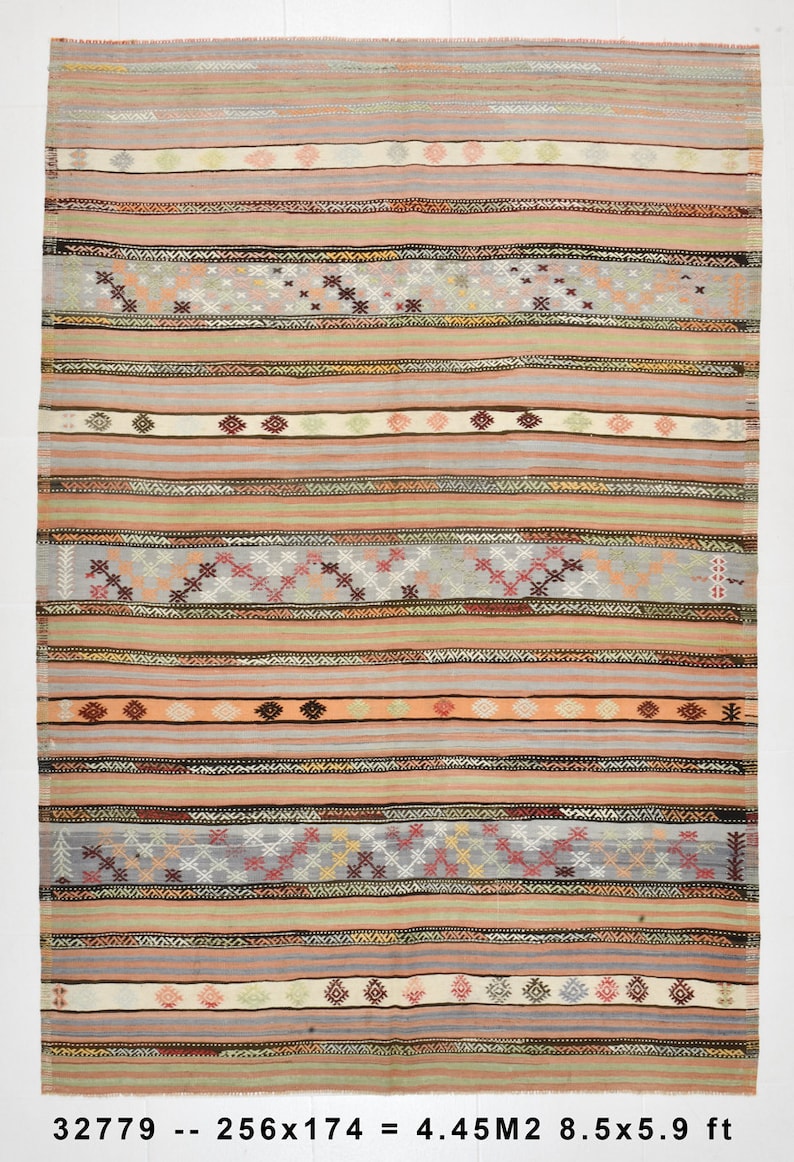 May include: A vintage rug with a striped pattern in shades of pink, beige, gray, and brown. The rug has a geometric design with small, repeating motifs. The rug is 8.5 feet by 5.9 feet.