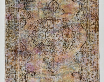 May include: A vintage rug with a faded floral pattern in shades of pink, blue, and brown. The rug has a distressed look and a worn border. It measures 9 feet by 5.4 feet.