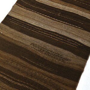 May include: A brown and beige striped woven rug with a textured surface.
