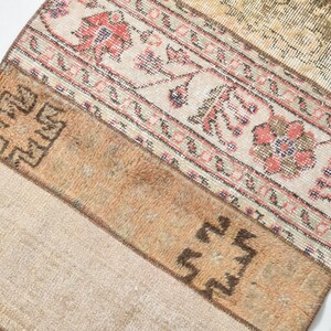 May include: A beige and brown patterned rug with a geometric design. The rug has a faded, vintage look and is made of woven fabric.