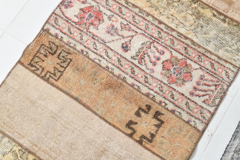May include: A beige and brown patterned rug with a geometric design. The rug has a faded, vintage look and is made of woven fabric.