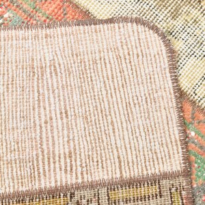 May include: Close-up of a beige and brown woven rug with a textured surface. The rug has a stitched edge and is made of different pieces of fabric.