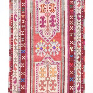 K&ouml;nnte beinhalten: Ein antiker t&uuml;rkischer Teppich mit einem geometrischen Muster in Rot, Rosa und Wei&szlig;. Der Teppich hat einen braunen Rand mit einem sich wiederholenden Sternmuster.
