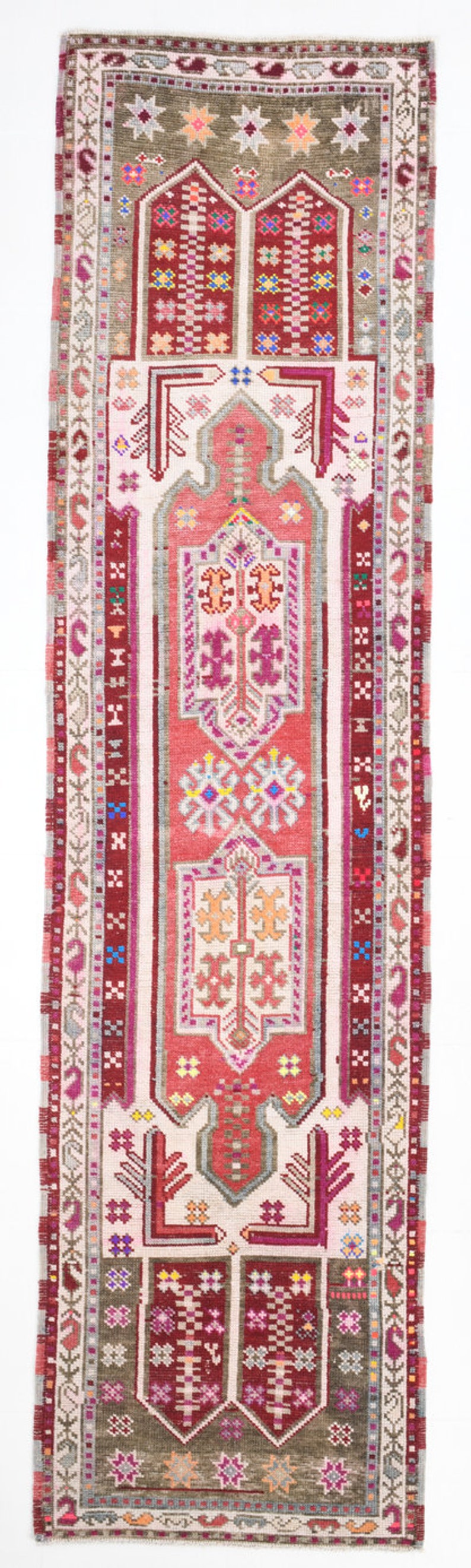 K&ouml;nnte beinhalten: Ein antiker t&uuml;rkischer Teppich mit einem geometrischen Muster in Rot, Rosa und Wei&szlig;. Der Teppich hat einen braunen Rand mit einem sich wiederholenden Sternmuster.