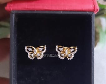May include: A pair of gold butterfly earrings with clear cubic zirconia stones. The earrings are in a black box with a red lid.