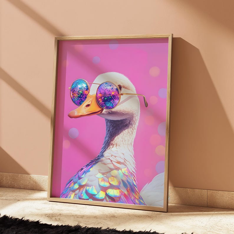 May include: A framed wall art print featuring a white goose wearing round, gold-rimmed sunglasses with iridescent, multi-colored lenses. The goose has iridescent feathers on its neck and chest, set against a vibrant pink background with soft bokeh circles.