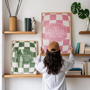 Peut inclure: Deux affiches murales rectangulaires dans des cadres en bois avec un motif à damier et le texte NO FUCKING SWEARING PLEASE. Une affiche présente un fond à damier rose et blanc, tandis que l'autre affiche un motif à damier vert et blanc.