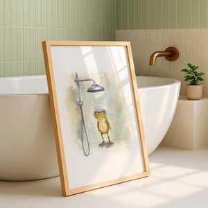 May include: A framed art print featuring a whimsical illustration of a frog wearing a shower cap under a shower head. The artwork has a light green and beige color palette, with a wooden frame. The print is displayed in a bathroom setting.