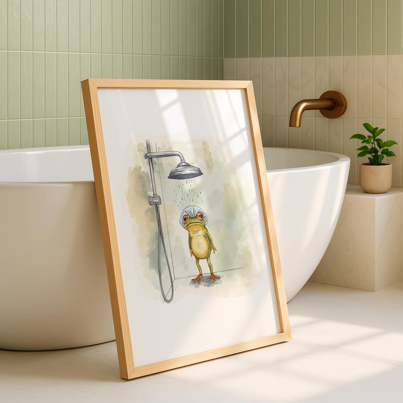 May include: A framed art print featuring a whimsical illustration of a frog wearing a shower cap under a shower head. The artwork has a light green and beige color palette, with a wooden frame. The print is displayed in a bathroom setting.