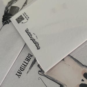Puede incluir: Tarjeta de felicitaci&oacute;n blanca con la palabra "BIRTHDAY" impresa. Se ve la esquina de otra tarjeta, con el texto "CHECK OUT OUR OTHER ITEMS HERE" y "the little print shop EST. 2020."