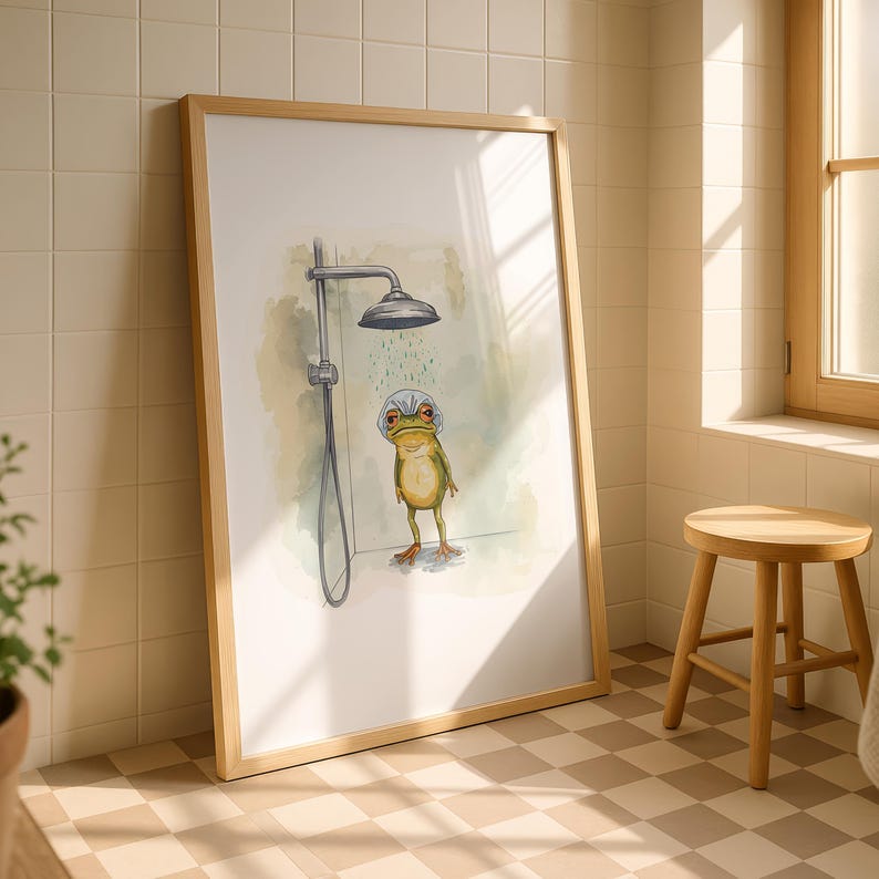 May include: A framed art print depicts a whimsical frog taking a shower. The frog, with a shower cap, stands under a shower head. The artwork is in a bathroom setting, with a wooden frame, a small wooden stool, and a window.