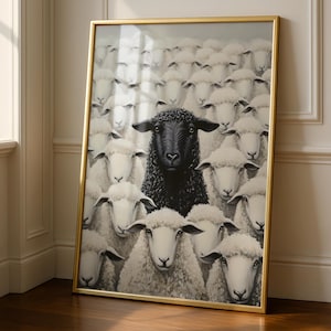 May include: A framed wall art print featuring a large flock of white sheep with a single black sheep positioned prominently in the center. The artwork is encased in a thin, metallic gold frame, showcasing a high-contrast composition of woolly animals.