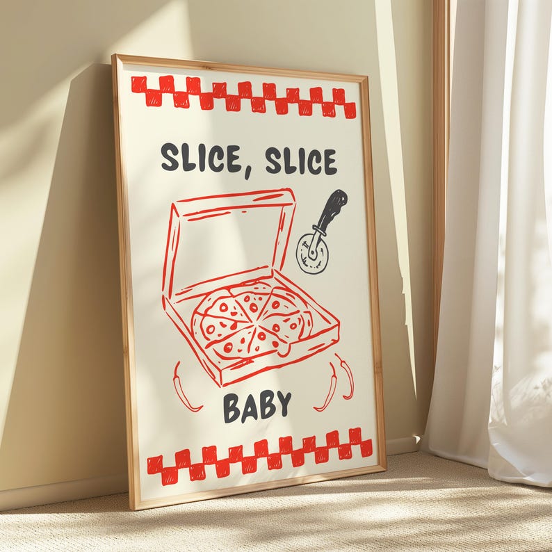 A framed print with a red and white checkered border, depicting a pizza box with a pizza inside, a pizza cutter, and the text "SLICE, SLICE BABY," leaning against a light-colored wall.