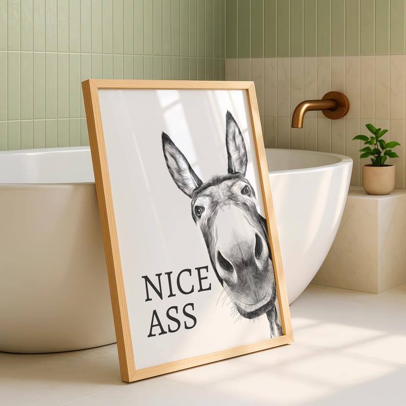 May include: A framed wall art print featuring a black and white charcoal-style illustration of a donkey's head looking forward. The text "NICE ASS" is printed in bold black capital letters on the left side of the white background within the frame.