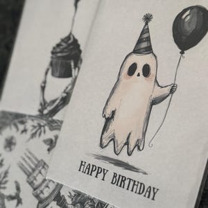 Puede incluir: Una tarjeta de cumplea&ntilde;os caprichosa con una ilustraci&oacute;n de fantasma. El fantasma, con un gorro de fiesta, sostiene un globo y tiene mejillas rosadas. Las palabras "HAPPY BIRTHDAY" est&aacute;n impresas debajo. La tarjeta es parte de un conjunto con otras ilustraciones.