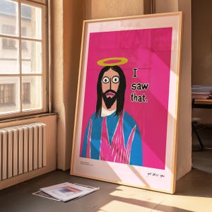 May include: A framed poster with a pink background featuring a cartoon illustration of Jesus with a halo. The text "I saw that." is written in black below the image. The poster has a wood frame and the text "god bless you" is written in the bottom right corner.