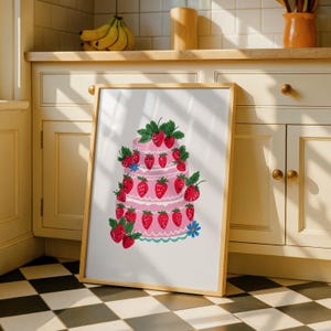 Peut inclure: Une impression d'art encadrée représentant un gâteau rose à trois étages décoré de nombreuses fraises rouges et de feuilles vertes. L'illustration comprend de petites fleurs bleues à la base et au sommet, sur un fond blanc dans un cadre en bois clair.