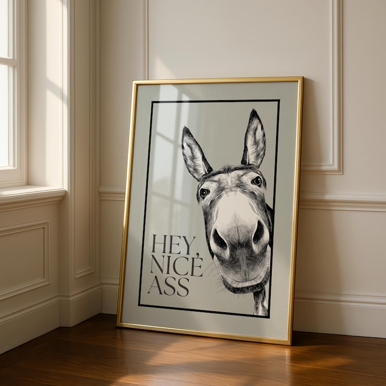 May include: Framed art print featuring a black and white illustration of a donkey's face. The artwork includes the text "HEY, NICE ASS" in a bold, sans-serif font. The frame is gold-colored, adding a touch of elegance to the humorous design.