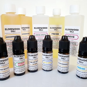 May include: A collection of 10 small glass bottles with black caps, filled with various scented oils. The bottles are labelled with the brand name "Elderwood Oils" and the scent names, including "Gingerbread", "Lemon Spritz", "Fresh", "Dove", "Coffee Mocha", "Rhubarb Custard", "Velvet Rose & Oud", "Lemon Spritz", "Gingerbread", and "Fresh".