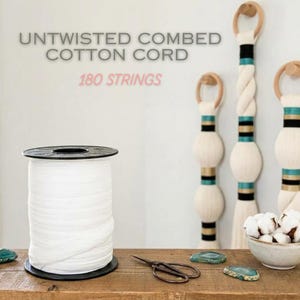Puede incluir: Una bobina grande de cordón de algodón peinado sin retorcer con 180 hilos. El texto UNTWISTED COMBED COTTON CORD y 180 STRINGS es visible. Tres tapices decorativos con detalles en color verde azulado, negro y dorado están al fondo.