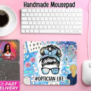May include: A handmade mousepad with an optician theme. The design features a woman with glasses and a messy bun, surrounded by eye exam charts and tools. The text "#OPTICIAN LIFE" is included. A keyboard, mouse, and pencil are also visible.