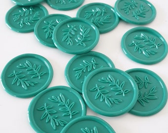 May include: A collection of teal wax seals with a leaf design. The seals are round and have a raised design.