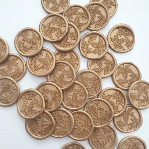 May include: A collection of bronze-coloured wax seals, each featuring a detailed maple leaf design. The seals are round and have a raised relief pattern. The image shows a scattering of these decorative seals.