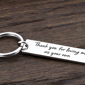 May include: Silver keychain with a rectangular tag that reads "Thank you for loving me as your own".
