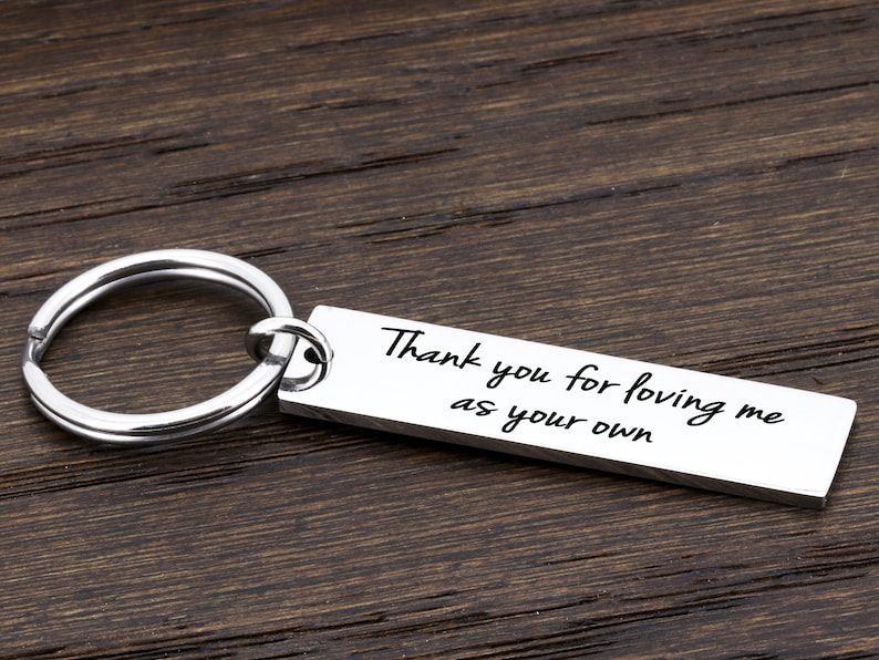 May include: Silver keychain with a rectangular tag that reads "Thank you for loving me as your own".