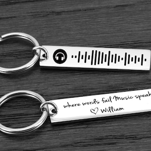 May include: Two silver keychains with engraved messages. The first keychain has a music note symbol and a barcode. The second keychain says "where words fail music speaks" with a heart symbol and the name "William".