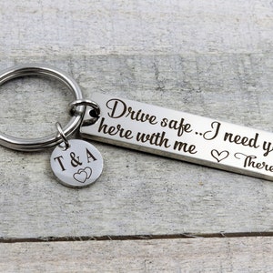 May include: Silver keychain with a rectangular tag that reads "Drive safe... I need you here with me" with a heart and the name "Theresa" engraved. A smaller charm with the initials "T & A" and two hearts is attached to the keychain.